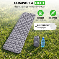 Compacte en lichte slaapmat met draagtas en reparatiekit, op het gras naast een waterfles