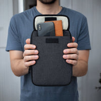 Man houdt een zwarte Travelhawk kabel organizer met telefoon en accessoires vast